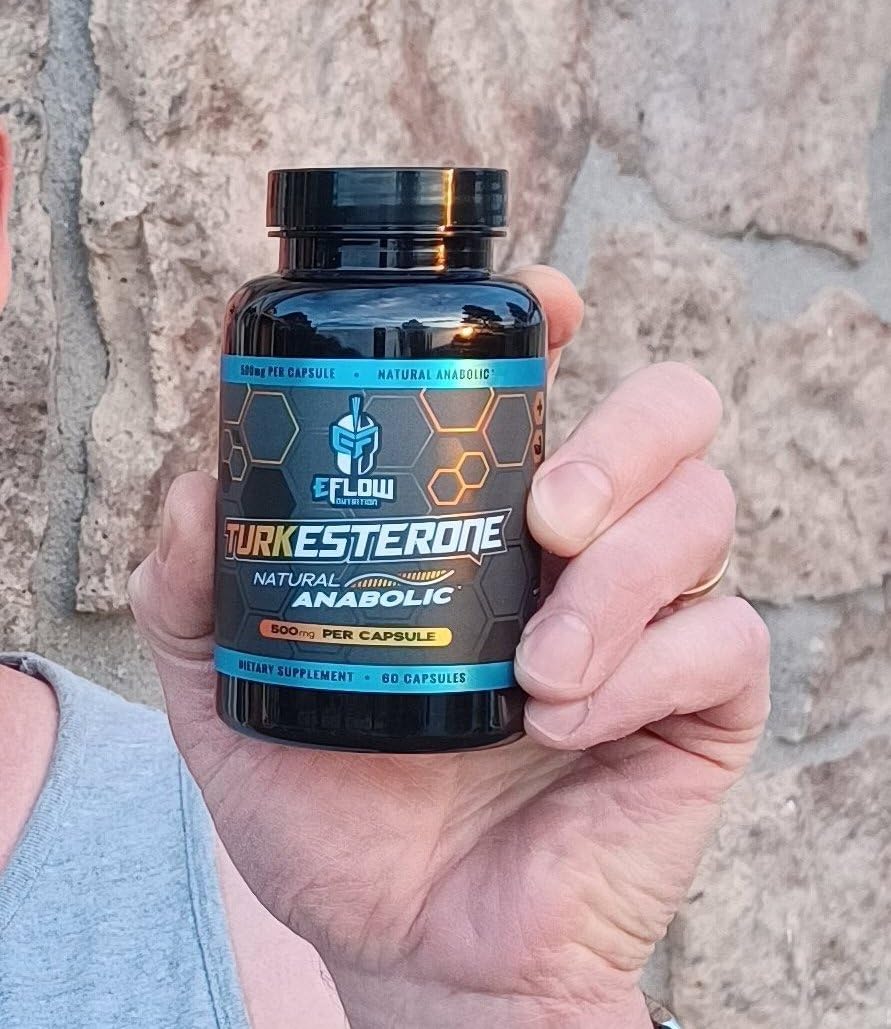 Customer holding a black eFlow Turkesterone bottle, 500 mg per capsule, in front of a stone wall